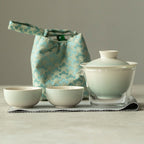 Tea set with a green patterned bag on a neutral background