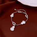 Silver bracelet with mother of pearl hulu-shaped charms on a red fabric background