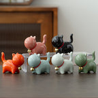 Set of colorful ceramic cat figurines on a reflective surface with a blurred background