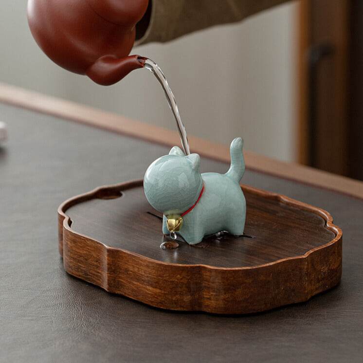 Ceramic cat-shaped figurine on a wooden base with a blurred background