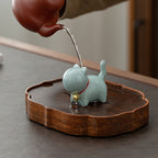 Ceramic cat-shaped figurine on a wooden base with a blurred background